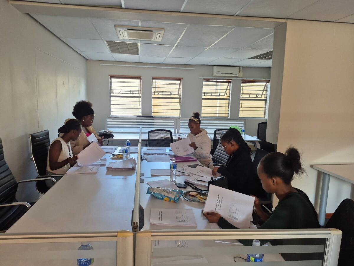 Kaylord administrators at the central office reviewing learner documentation and stipend reconciliation records.